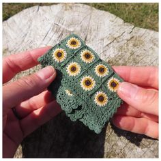 a hand holding a crocheted piece of cloth with sunflowers on it