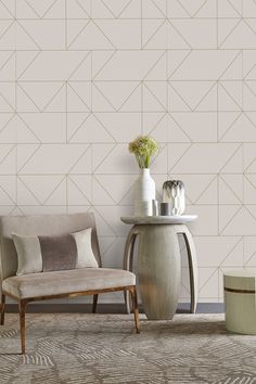 two chairs and a table in front of a wall with geometric designs on it,