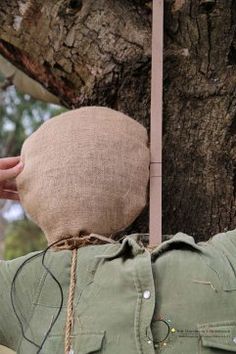 someone is holding their head up to a tree with an old hat on it's back