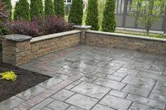 an outdoor patio with stone walls and landscaping