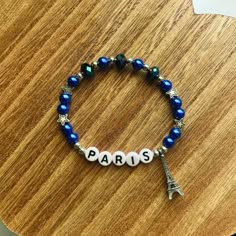 a bracelet with the word paris written on it and a eiffel tower charm