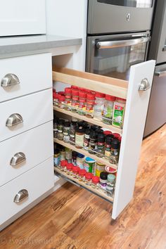 an open cabinet in the middle of a kitchen with spices and condiments on it