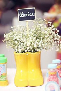 a yellow vase with baby's breath flowers and a chalkboard sign on it