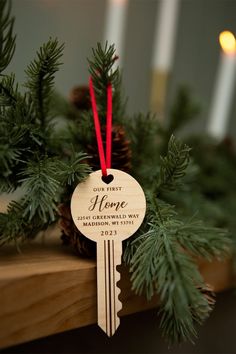 a house key ornament hanging from a christmas tree with red ribbon and pine cones