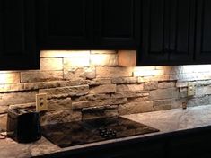 a kitchen with black cabinets and stone backsplash