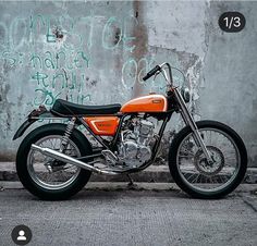 an orange and black motorcycle parked in front of a wall