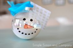 a snowman ornament with a blue bow on it sitting on a table