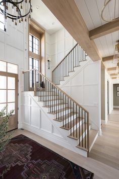 there is a staircase in the middle of this house with white walls and wood floors