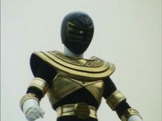 a man in a gold and black costume with his hands out to the side,