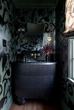 a bathroom with black and white wallpaper, gold fixtures and a vanity in the corner