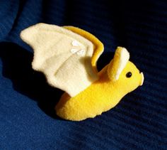 a yellow stuffed animal with white wings on a blue surface and the back side of it's body