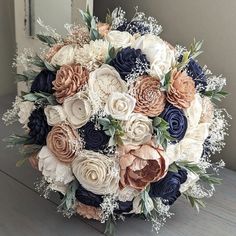 the bridal bouquet is made up of blue, white and peach flowers with baby's breath