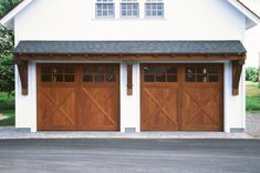 two wooden garage doors in front of a white house