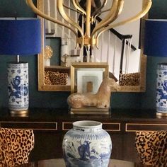 a blue and white vase sitting on top of a table next to two gold lamps