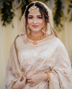 a woman wearing a white and gold bridal outfit