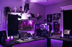 a computer desk with two monitors on top of it and purple lighting in the background