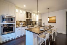 a kitchen with white cabinets and an island in the middle is lit by pendant lights