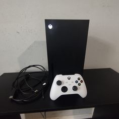 a white controller sitting on top of a wooden table next to a black box with wires