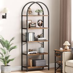 a living room filled with furniture and a book shelf next to a plant on top of a hard wood floor