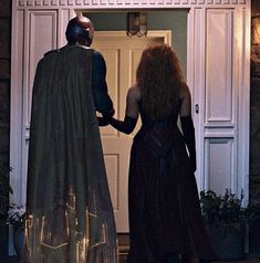 two people dressed in costumes are standing at the door