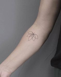 a person's arm with a small flower tattoo on the left side of their arm