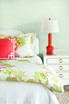 a bedroom with green walls, white bedding and red pillows on the headboard