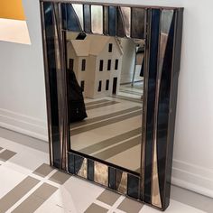 a mirror that is sitting on the floor in front of a wall with a house