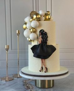 a white cake with black and gold decorations on it's side, sitting on a table