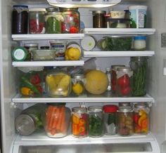 an open refrigerator filled with lots of different types of vegetables and fruit in jars on the shelves