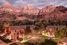 an aerial view of a home in front of the mountains at dusk with lights on