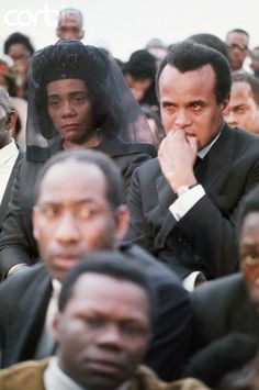 a group of people sitting next to each other in front of a crowd wearing suits and ties