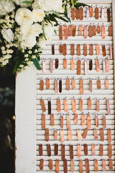 a wooden peg board with clothes pins attached to it and flowers in front of it