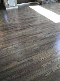 an empty living room with hard wood flooring in it's center and sun shining through the window