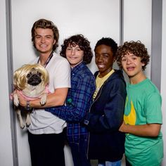 a group of young men standing next to each other holding a small pug dog