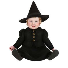 a baby wearing a black witch costume sitting on the ground with her hands in her pockets