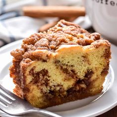 a close up of a piece of cake on a plate with a cup of coffee in the background