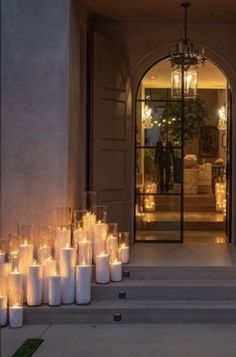 many lit candles are on the steps in front of a building with an entrance and chandelier