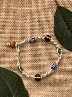 a bracelet that has beads on it and some green leaves next to the bead