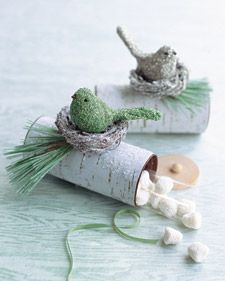 two small birds sitting on top of some white pipe with grass in it's beaks