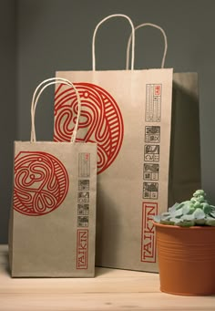 two brown bags sitting on top of a wooden table next to a potted plant