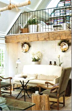 a living room filled with furniture and lots of wood beams on the wall above it