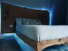 a bed with a wooden headboard and foot board in a room that has blue lights on the walls