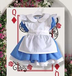 a dress with blue and white ruffles on the bottom is sitting in front of flowers