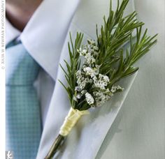 a boutonniere with white flowers and greenery is worn on the lapel of a man