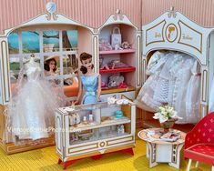 two dolls are in a doll house with dresses on display