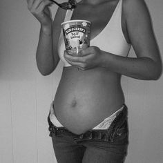 a pregnant woman is eating yogurt and holding a spoon