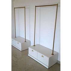 two white dressers with gold handles in an empty room