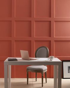 a laptop computer sitting on top of a white table next to a chair and wall