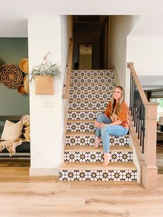 a woman is sitting on the stairs in her home