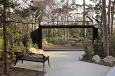 a black bench sitting in the middle of a forest next to rocks and trees with a large screen behind it